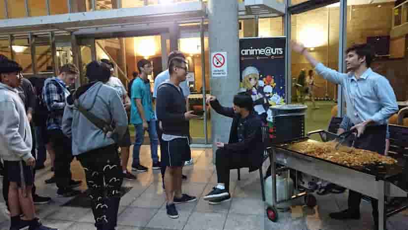 A group of members waiting for yakisoba to be cooked on a BBQ